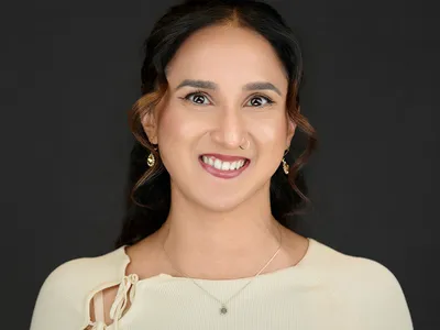 Young professional woman in cream blouse with bow detail and delicate earrings, bright smile