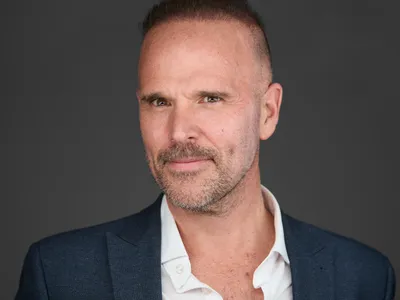 Executive man with shaved head and goatee in navy blazer and white shirt, confident expression