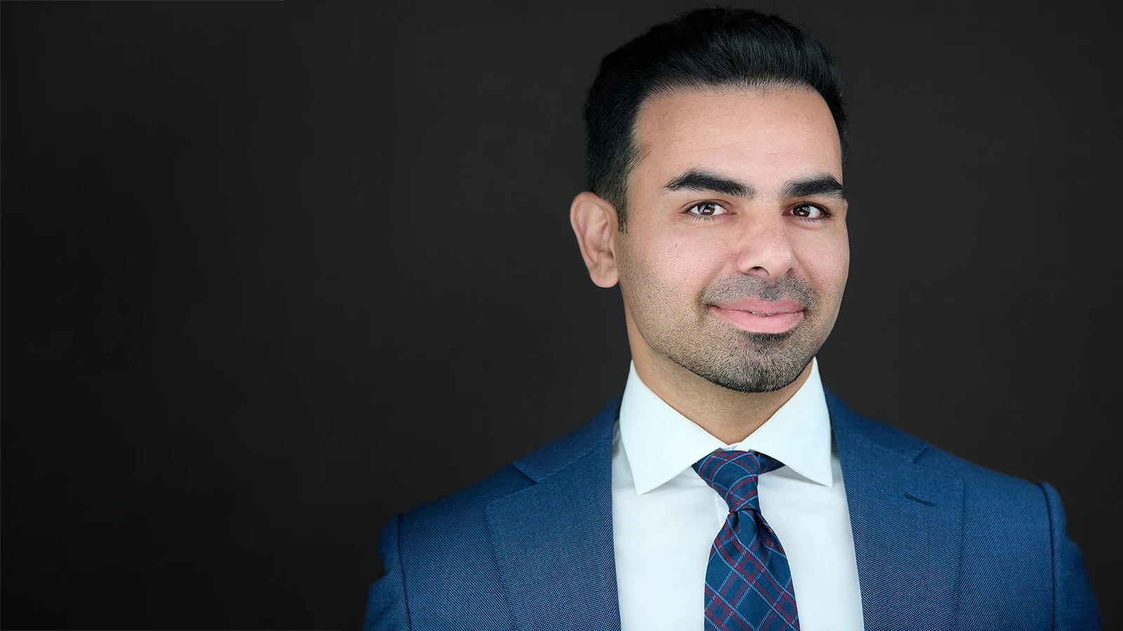 Professional headshot on a dark background with clear space for headline text.