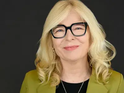 Corporate headshot of blonde professional woman with glasses wearing yellow blazer, showcasing confident and approachable style for corporate team photography