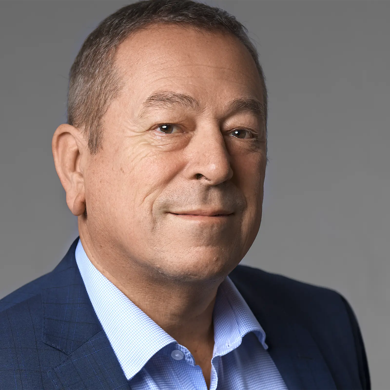 Professional business headshot of a man in a blue suit. Image was captured in an onsite mobile studio