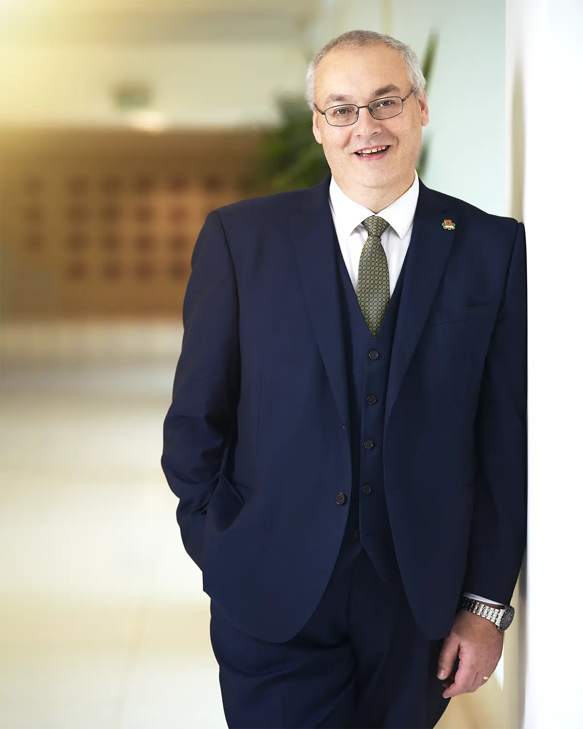 Professional Business Portrait of a man in a blue suit leaning against the wall of an office