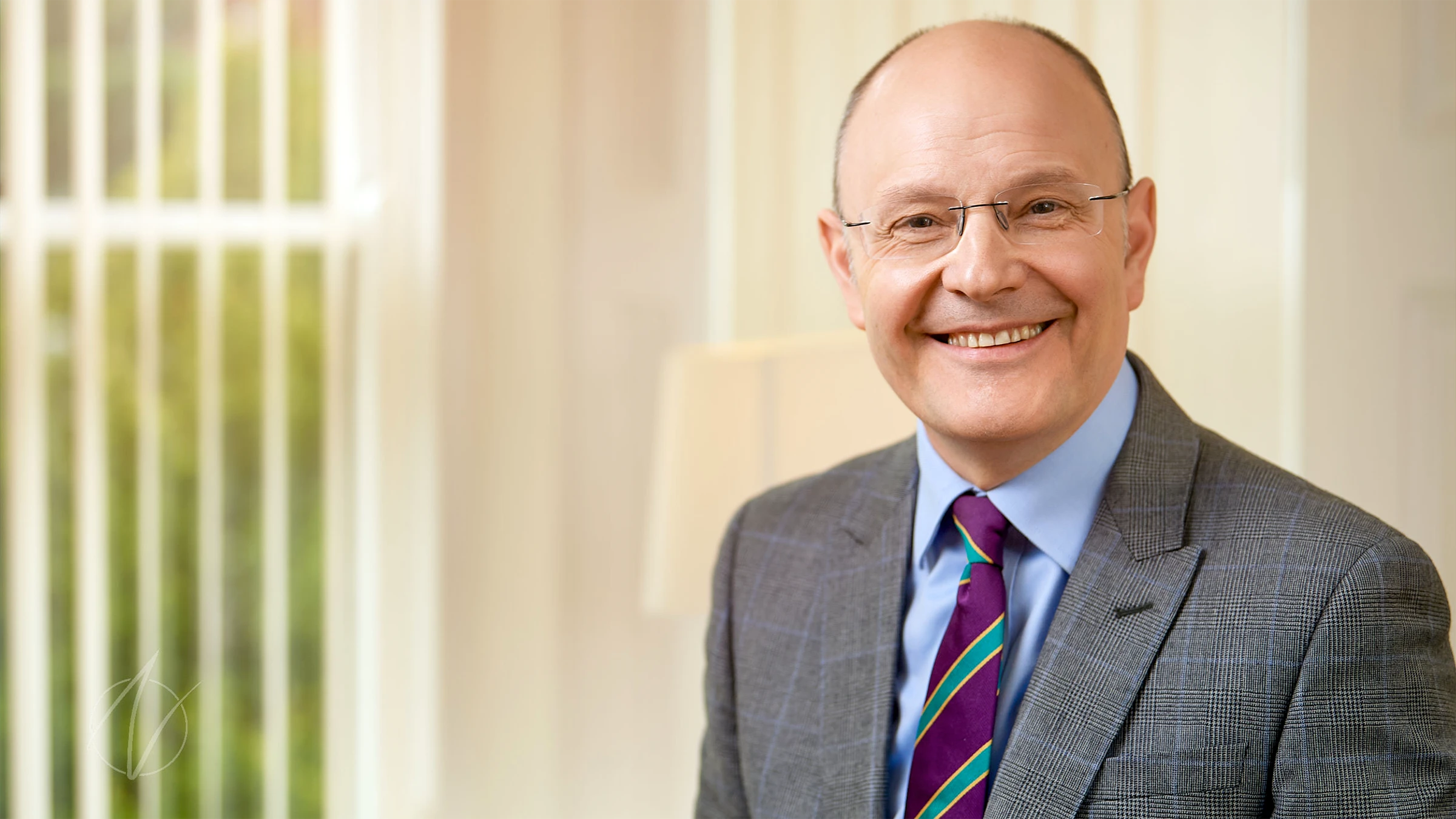 Lifestyle branding headshot photography of businessman in a suit seated in a bright office