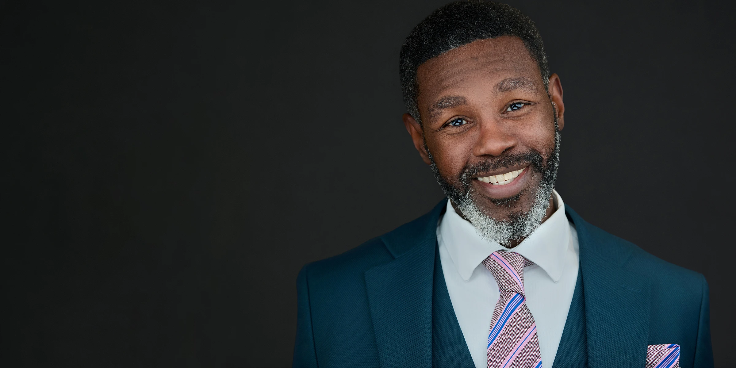 Professional business headshot portrait with confident expression on a dark studio background