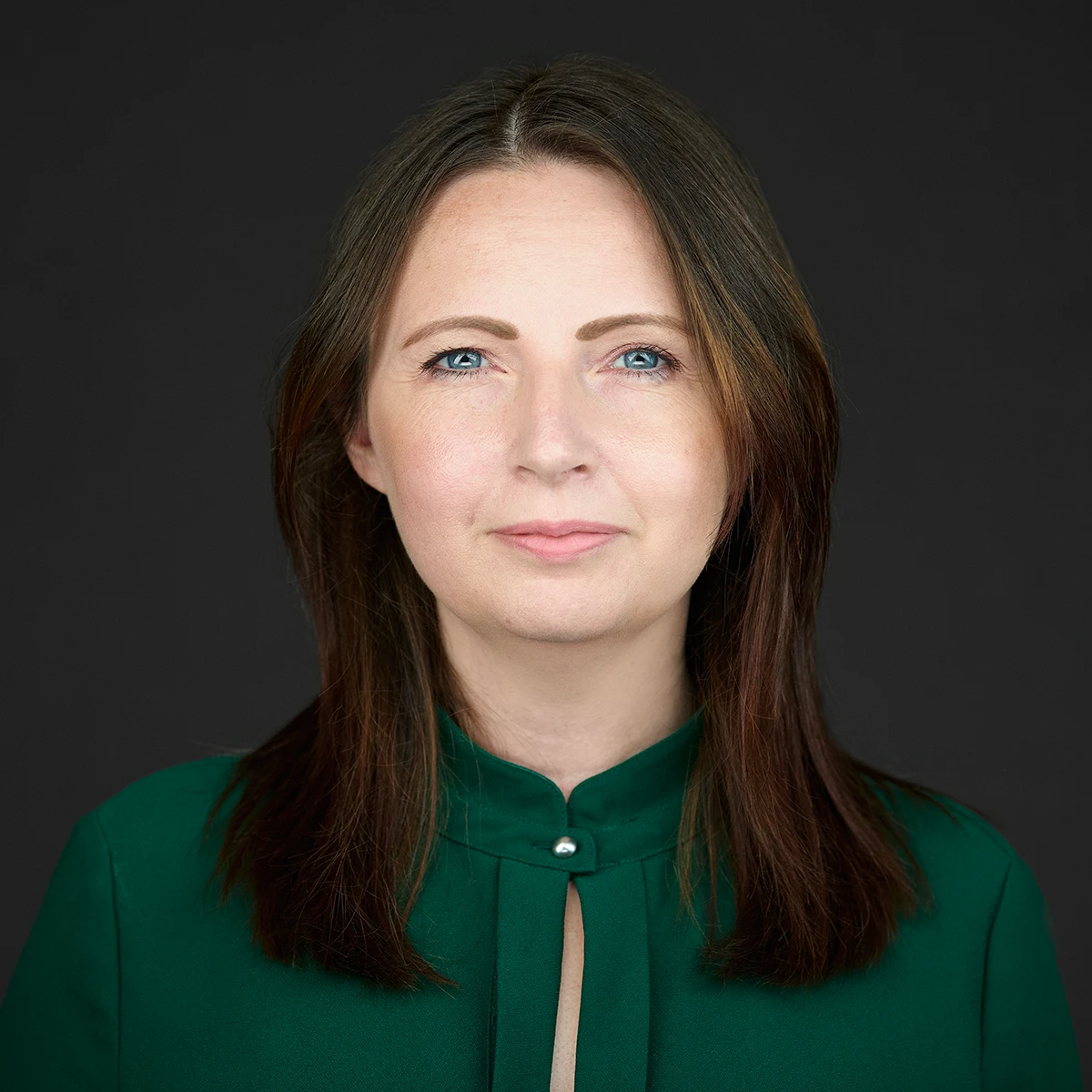 Professional business headshot of a woman in a green top with long brown hair