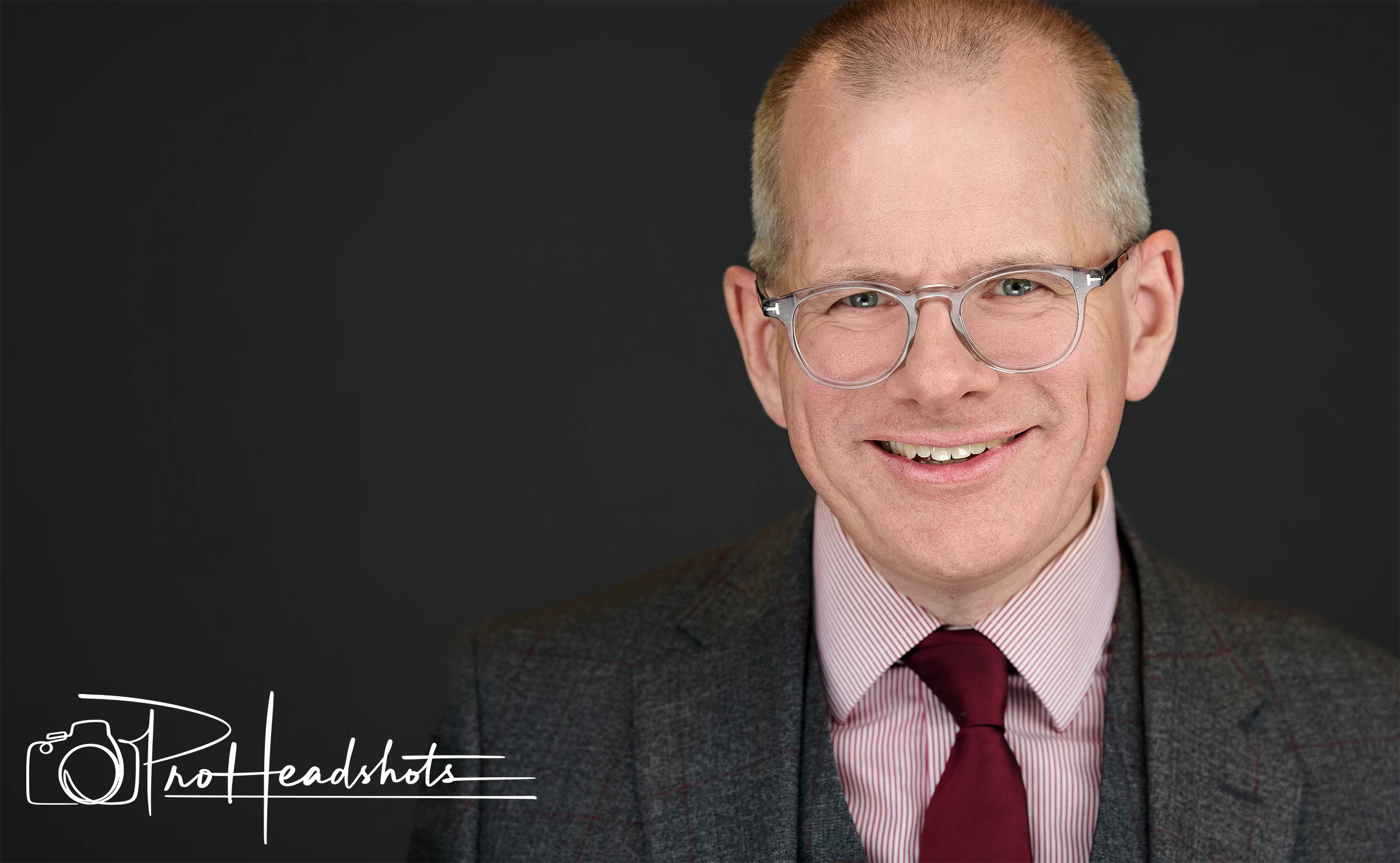 Head shot portrait of a man wearing glasses with a suit and red tie