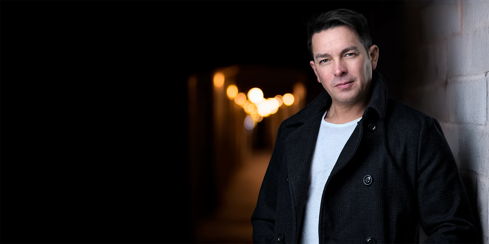 Actor portrait of Davey Jones in a darker, cinematic setting with warm background lights