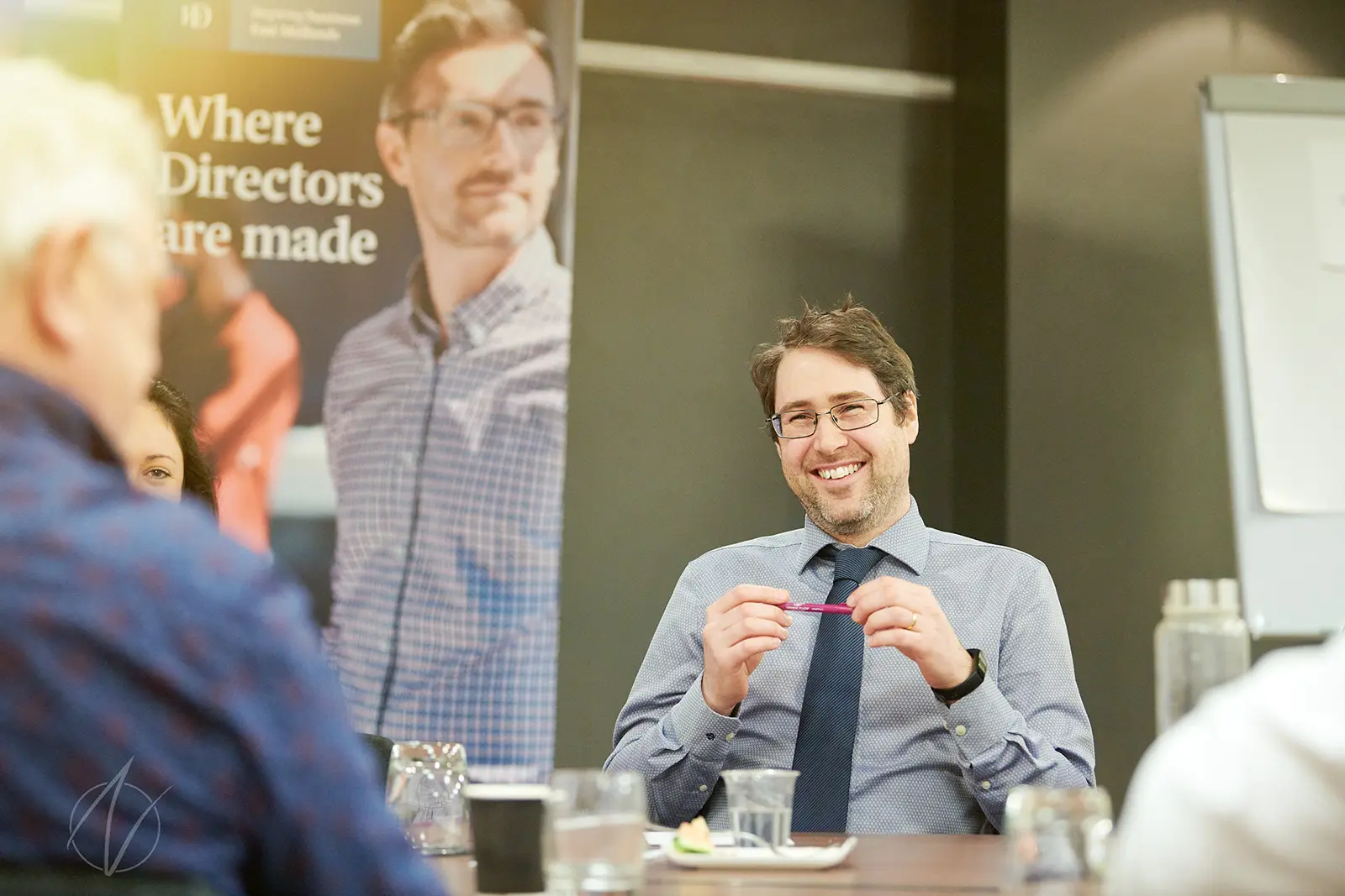 Personal branding photography of a businessman in a meeting, smiling, captured on-site at his office by Peter Nutkins.