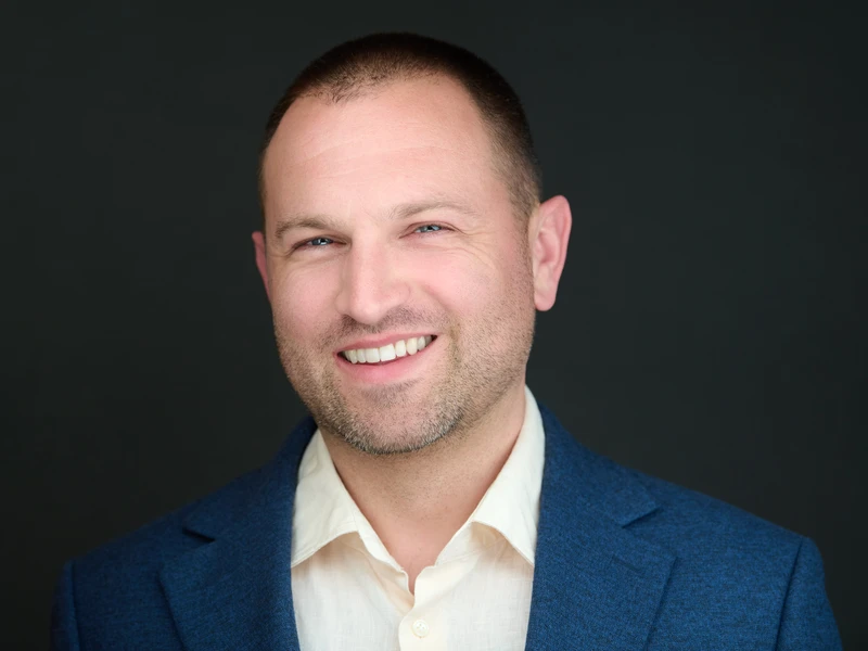 Executive portrait of a man in a navy jacket on a dark background