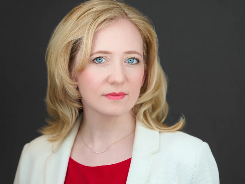Business portrait of a woman in a white blazer on a dark background