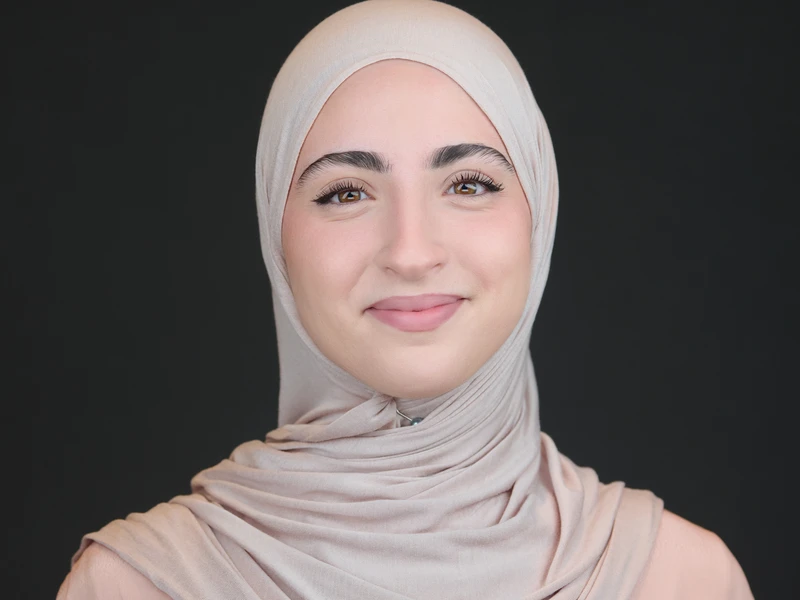 Professional portrait of a woman wearing a headscarf on a dark background