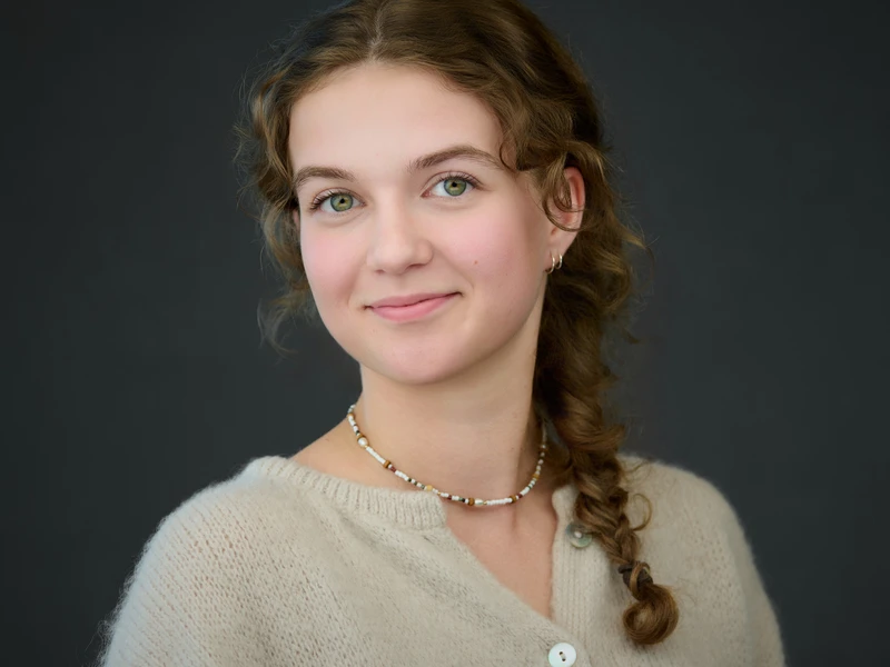 Modern headshot of a young woman with braided hair on a dark background