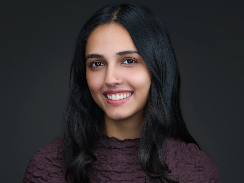 Modern headshot of a woman with long dark hair on a dark background