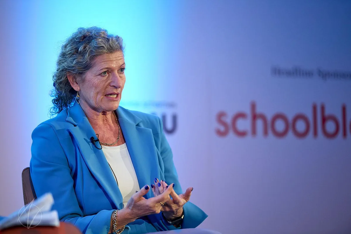 Professional in blue blazer making a point during a panel discussion at a business event