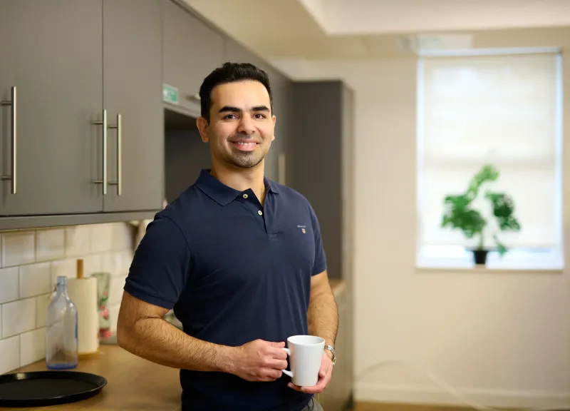 Ben Rahmani relaxed in the kitchen area holding a mug, personal branding photography Bournemouth