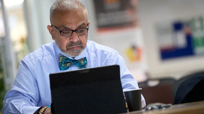 Christian Kumar working at a desk with documents and a laptop, executive personal branding photography