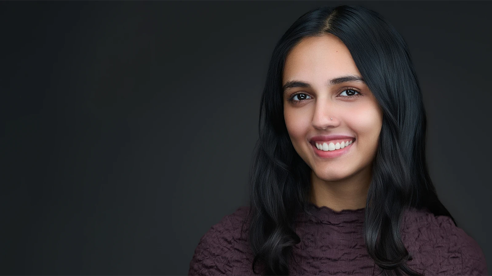 Professional headshot of a woman with long dark hair and a warm smile