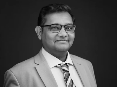 Black and white portrait of a man in a suit and glasses, composed professional expression