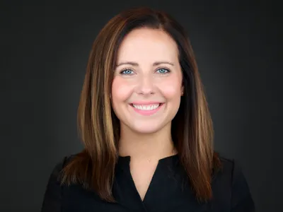 A professional woman in a silk blouse, warm studio lighting against a dark background