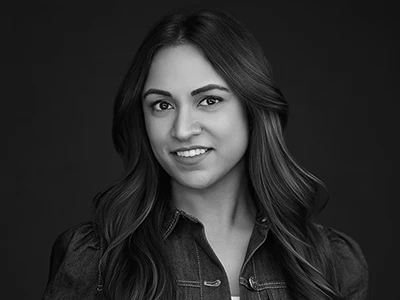 Black and white headshot of a woman in a dress shirt, looking composed and professional