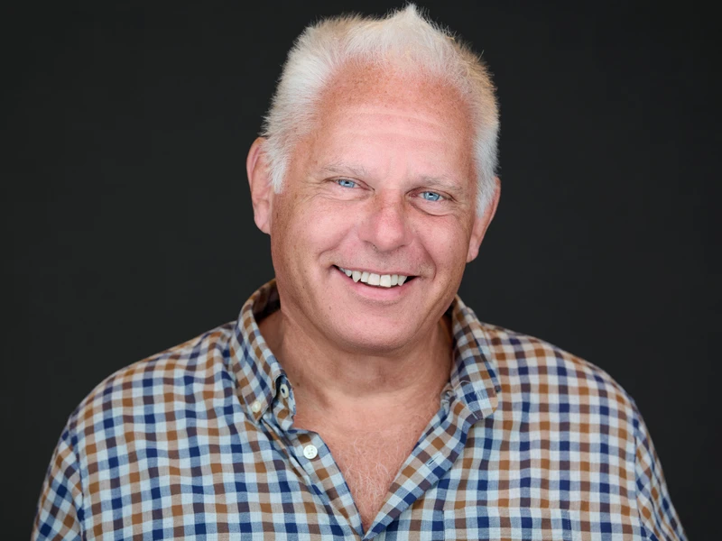 Man in dress shirt, relaxed and direct expression, clean dark-background headshot