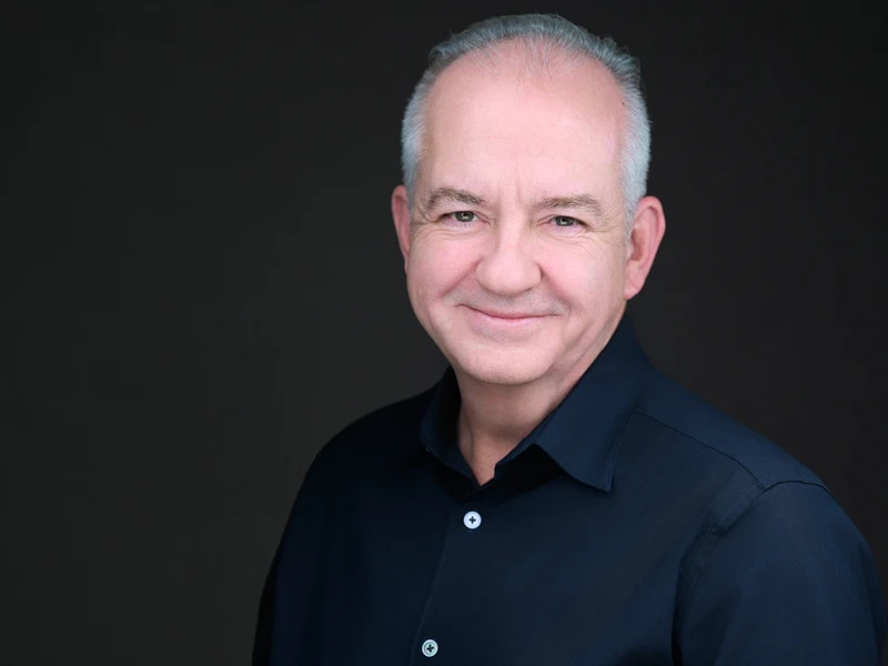 Headshot of a man in a dress shirt on a dark studio background