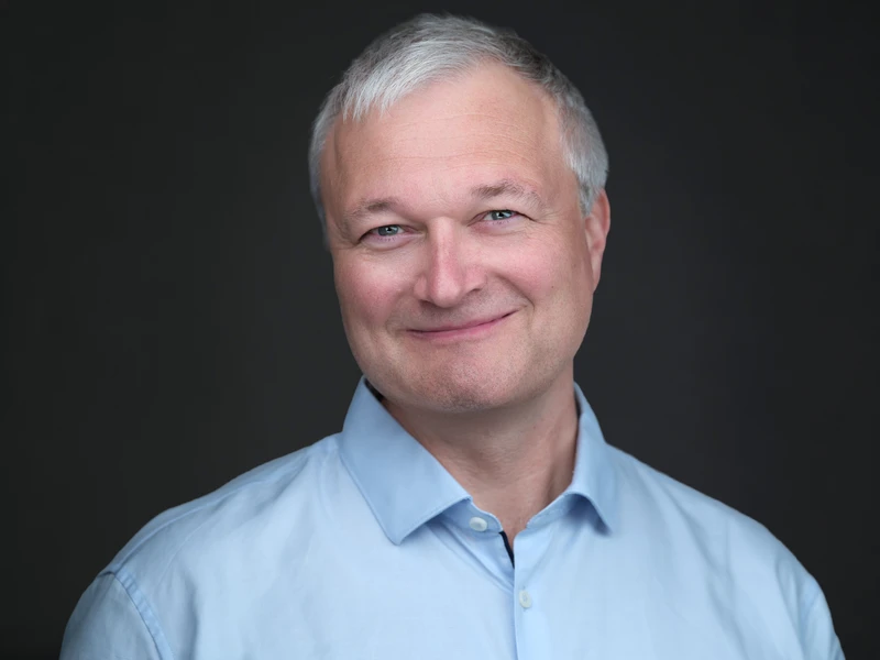 Headshot of a man in a dress shirt, relaxed look on a dark studio background