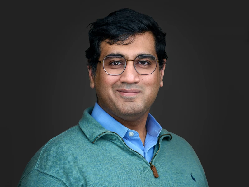 Man in glasses and a knitted jumper, relaxed friendly expression — professional headshot