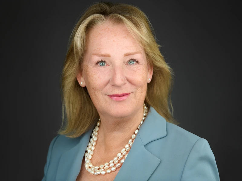 London professional headshot of a woman in a dark blazer, confident expression, on a studio background