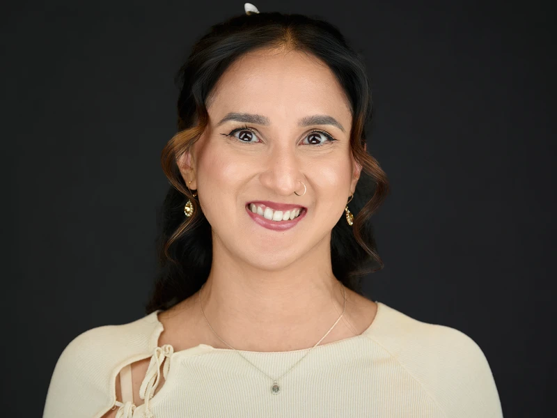 Professional portrait of a woman in a dark grey blouse with warm studio lighting