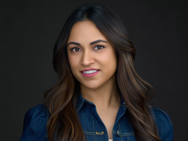 Woman in a crisp dress shirt, warm confident smile — professional headshot