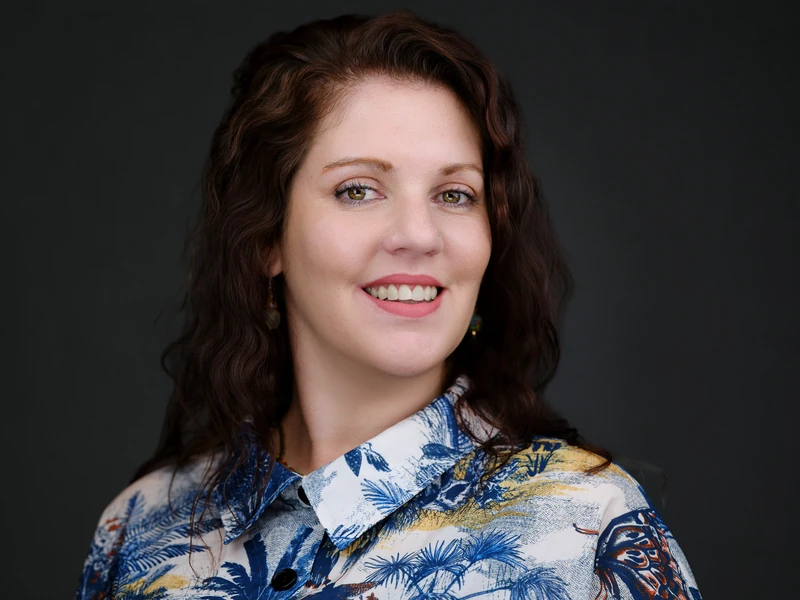 Woman in a patterned blouse, natural confident expression in a studio portrait