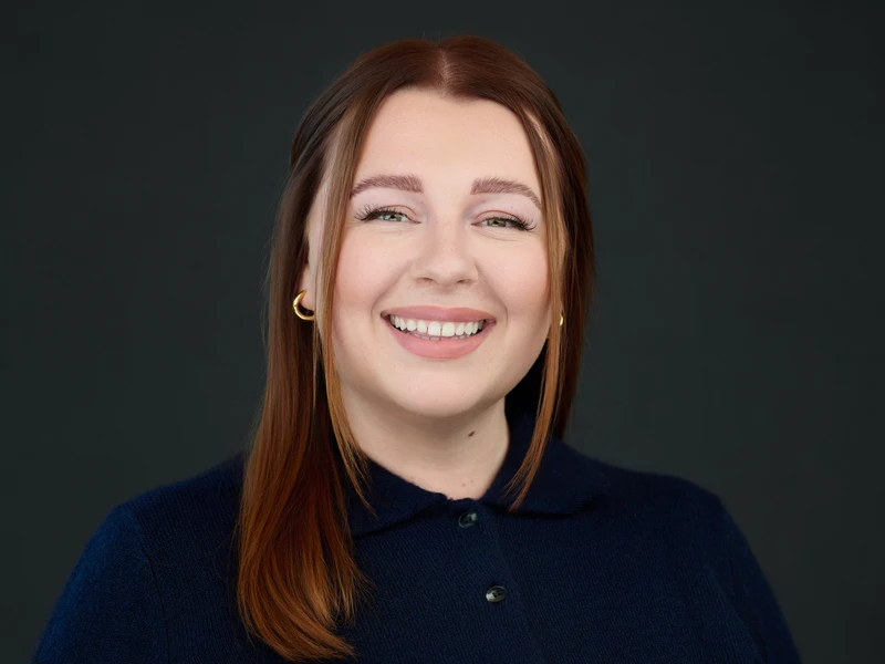 Red-haired woman in polo shirt, natural smile, approachable professional portrait