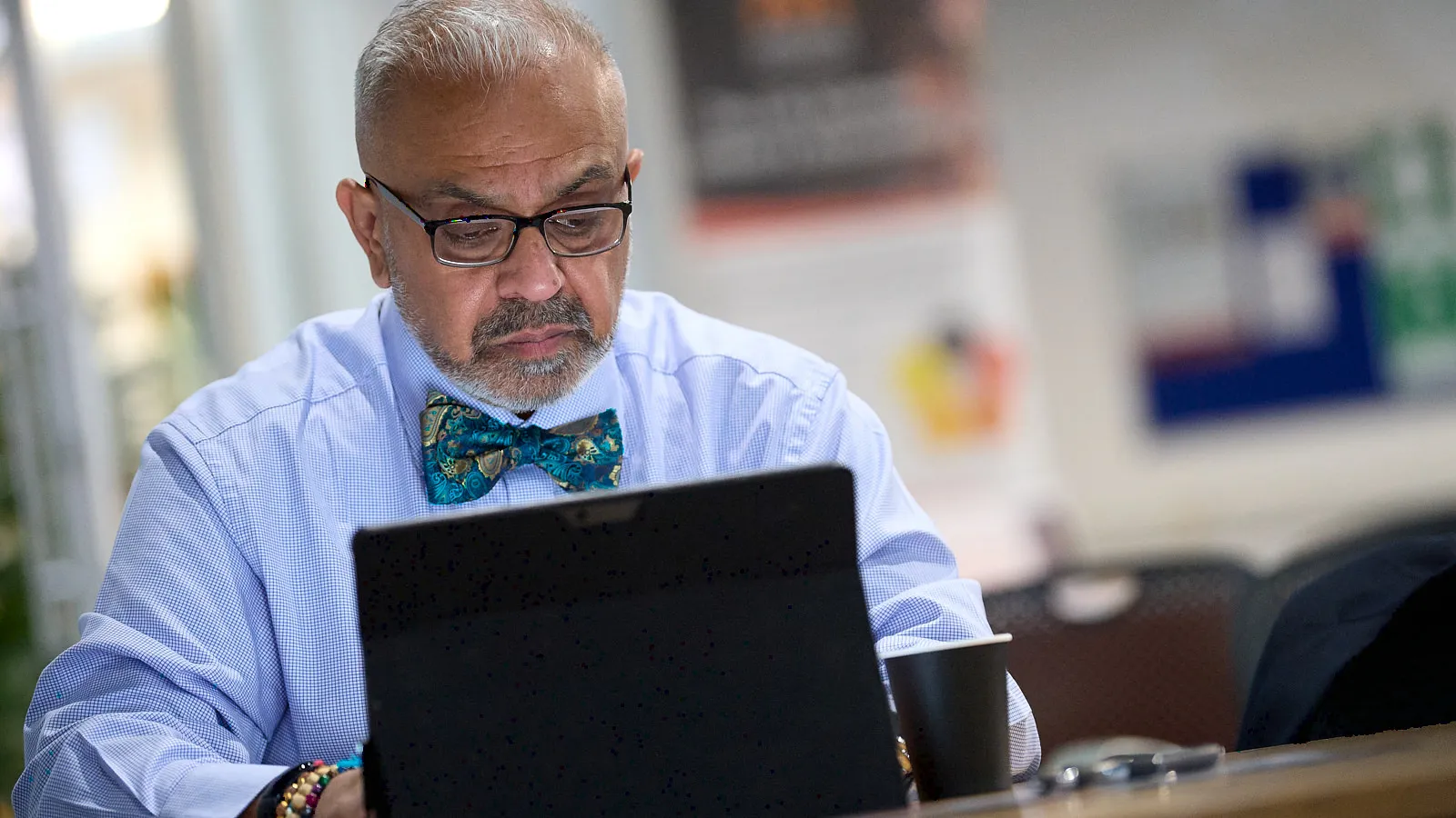 Consultant in glasses and bow tie working at a laptop in a co-working space