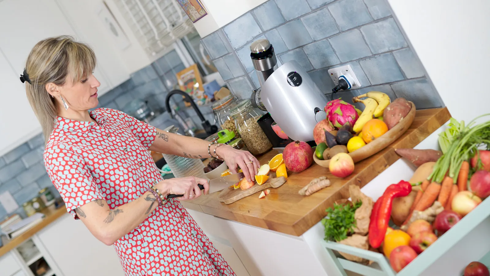 Food professional in a red floral dress preparing fresh produce in a bright kitchen